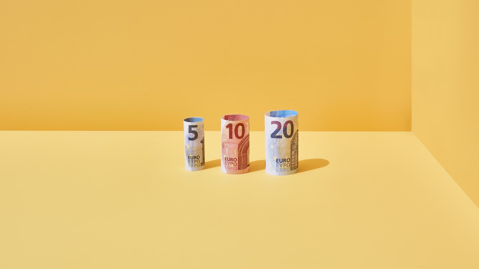 Farbige kuenstlerische Bilder die Geld darstellen. Hintergrund rot, gelb, orange oder gruen. Darstellung von Münzrollen, Geldscheinen und Münzen