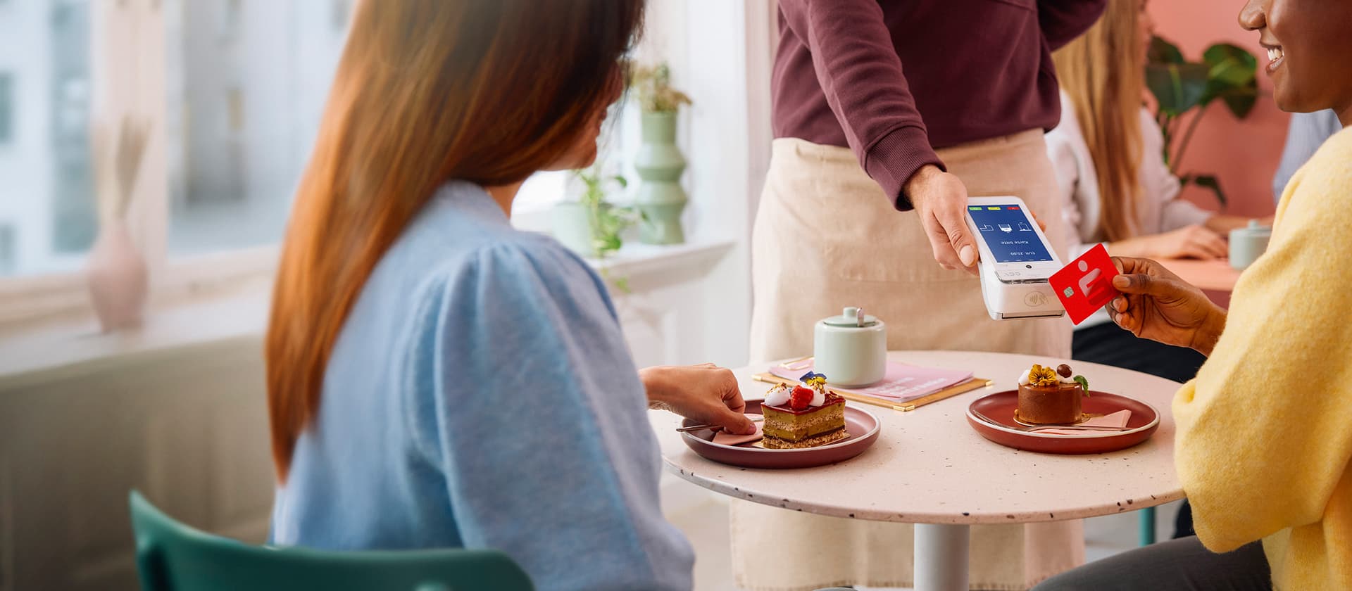 Person bezahlt mit Sparkassen-Card kontaktlos am Kartenlesegerät im Café