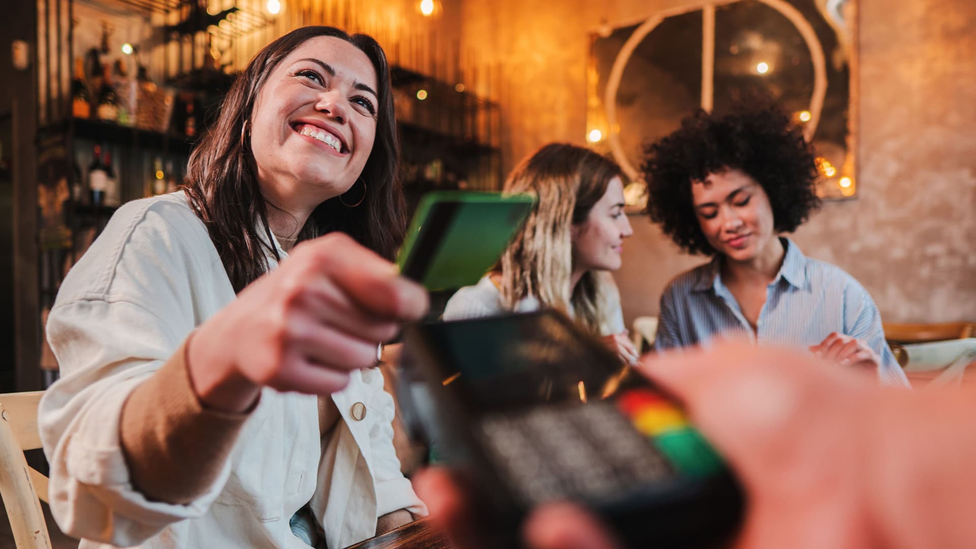 Eine junge Frau bezahlt in einem Restaurant mit einer Karte