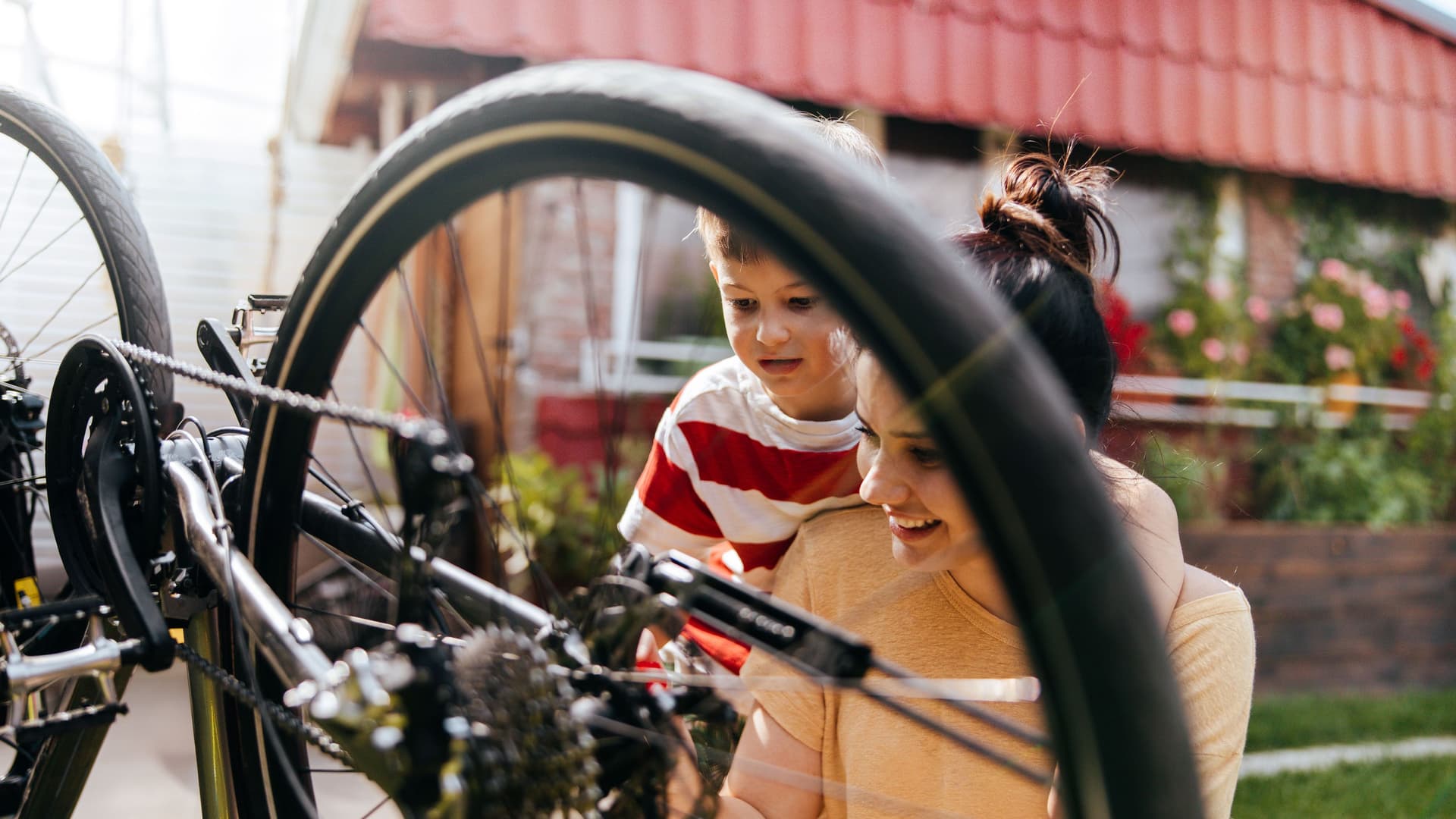 Foto von Mutter und Sohn, die in ihrem Garten ein Fahrrad reparieren.