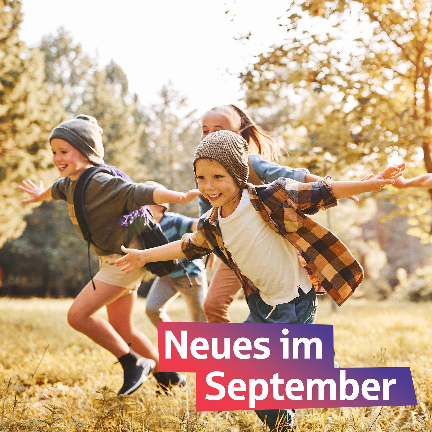 Fröhlich Kinder rennen bei Sonnenschein durch den Park. Auf dem Bild steht "Neues im September"