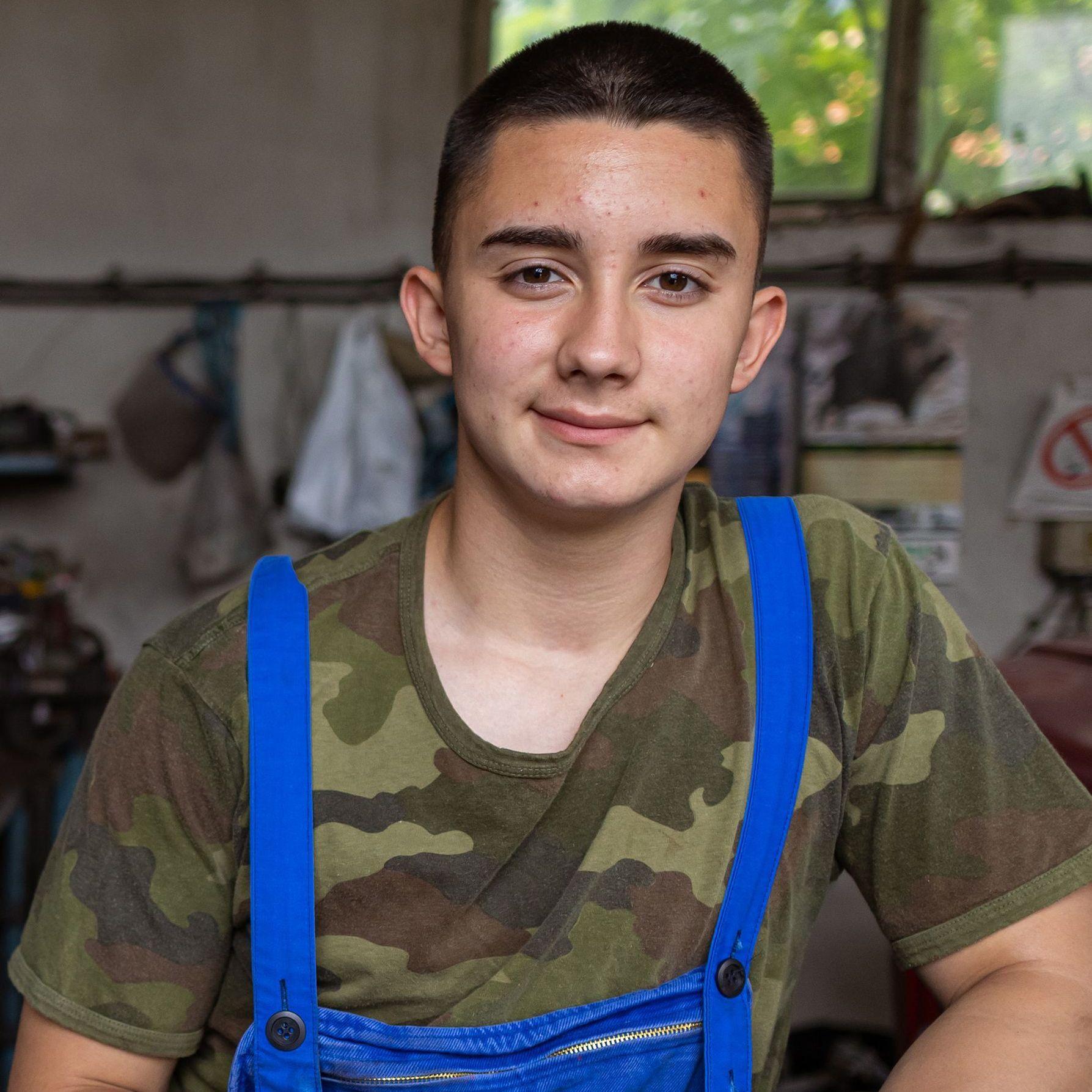 Fachkräftemangel Ein junger Mann in Camouflage T-Shirt und Blaumann sitzt in einer Werkstatt
