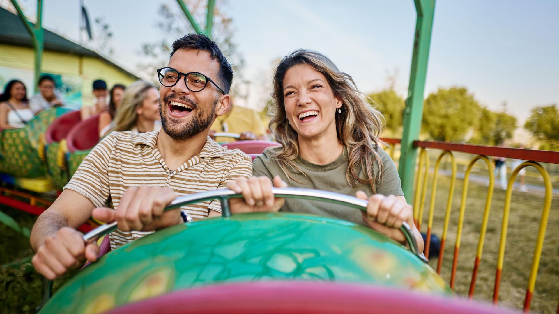 Junges Paar im Frezeitpark. Sie fahren mit einem Fahrgeschäft.