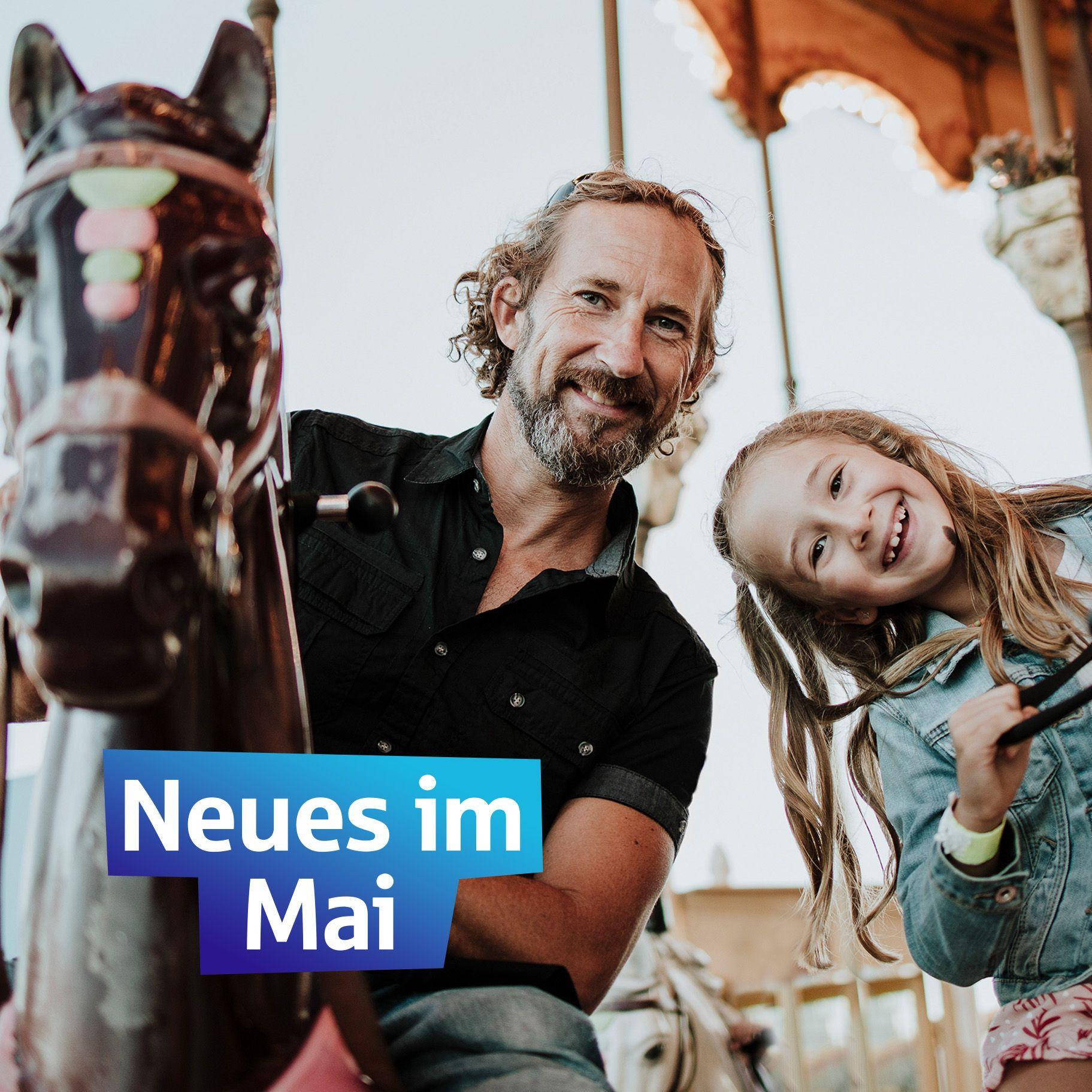 Neues im Mai, ein Mann und ein Kind auf einem Karussell, in weißer Scjrift auf blau steht "Nues im Mai"
