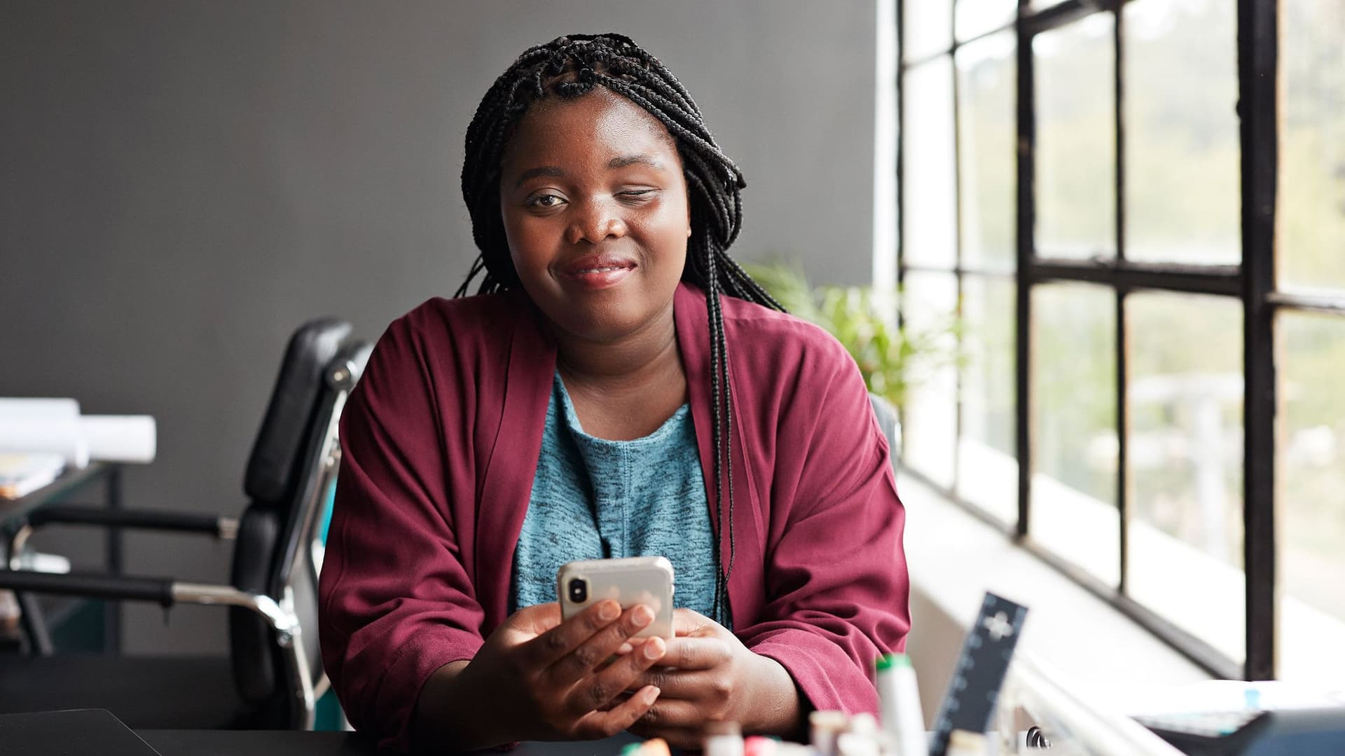 Frau mit Sehbehinderung und Handy am Schreibtisch