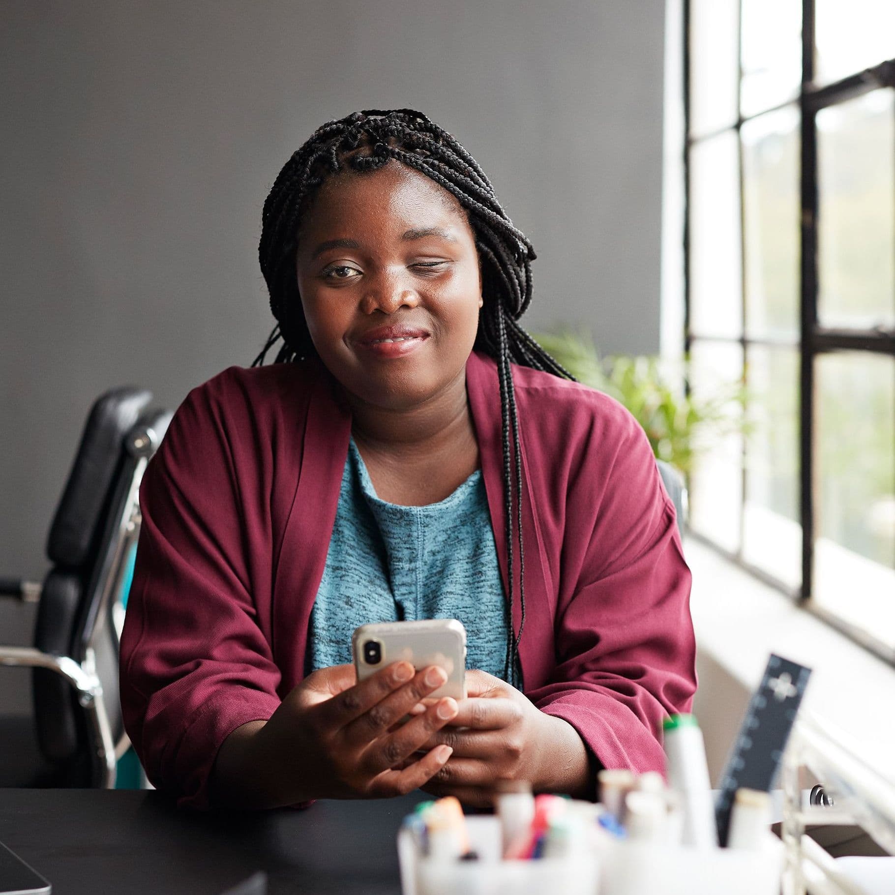 Frau mit Sehbehinderung und Handy am Schreibtisch