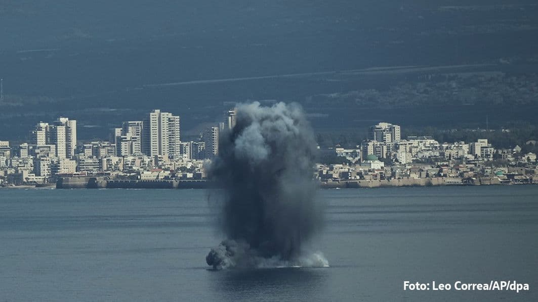 Große schwarze Rauch- und Wassersäule steigt nach Explosion vor einer Küstenstadt auf.