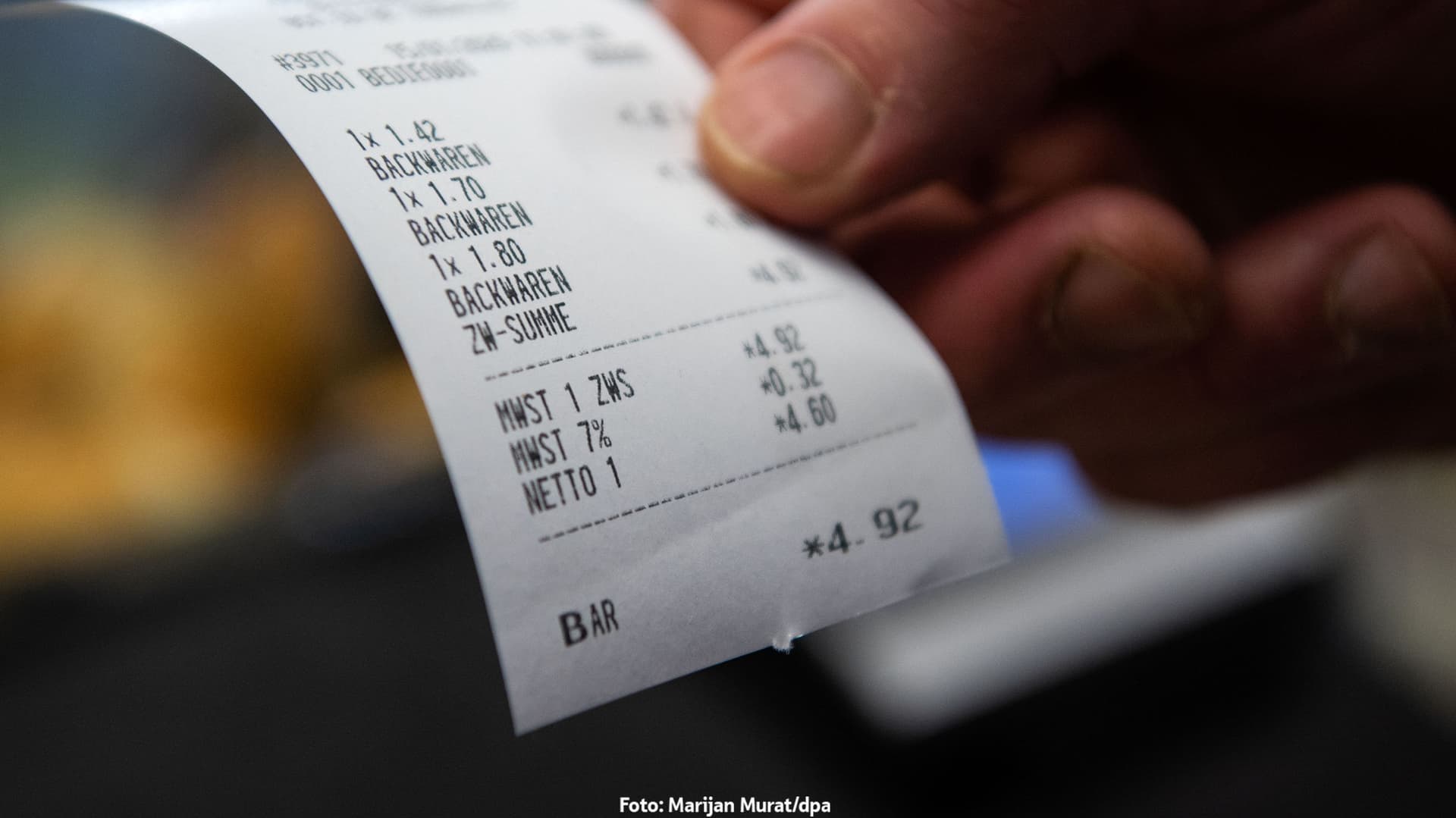 Eine Hand hält einen gedruckten Kassenbon einer Bäckerei über drei Backwaren mit einer Gesamtsumme von 4,92 Euro, bar bezahlt.