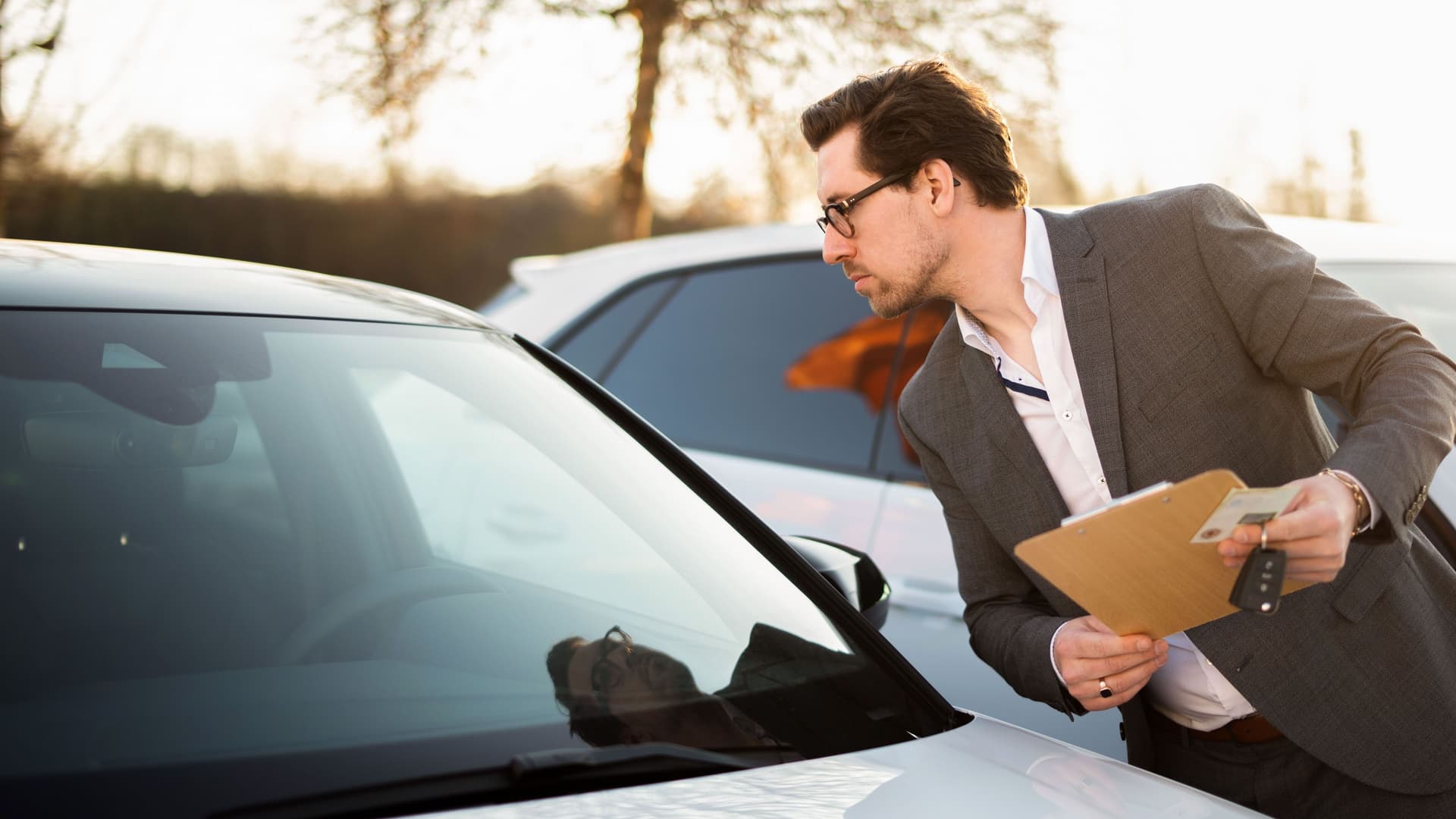 Ein Autoverkäufer schaut sich die Windschutzscheibe eines Autos an.