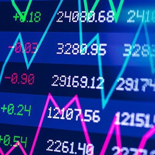 Ein seitlich fotografierter Bildschirm mit Aktienkursen. Über die Kursdaten sind verschiedenfarbige Verlaufslinien gelegt.