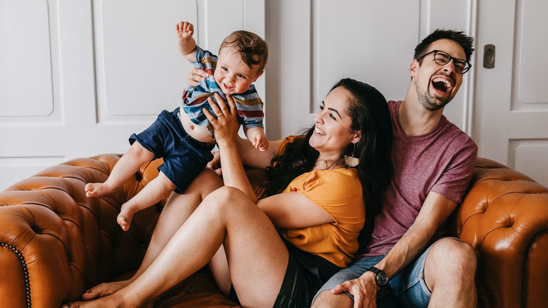 Junge lachende Familie auf Ledersofa