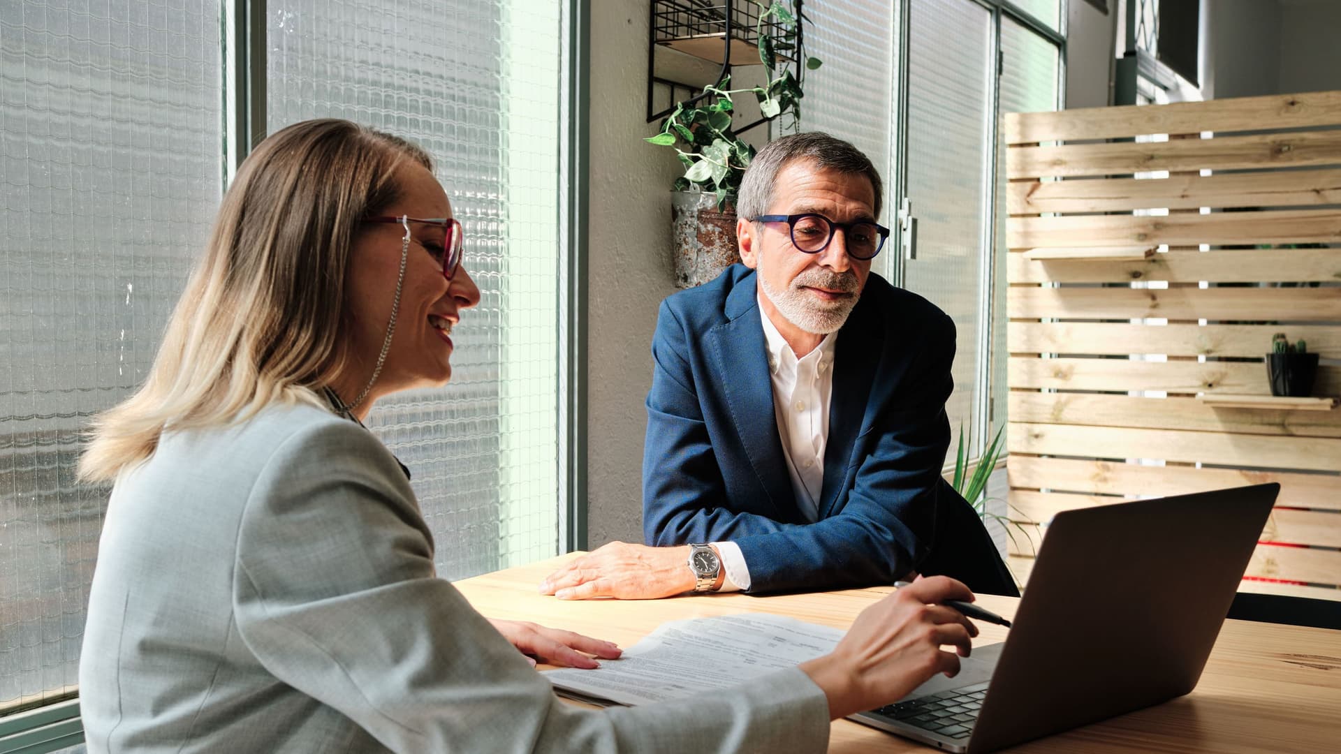 Eine Frau und ein Mann sitzen in einem Büro vor einem Laptop.