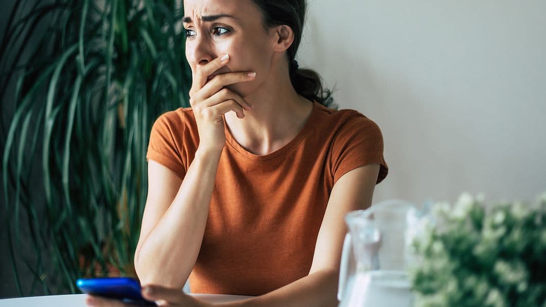 Eine junge Frau ist verzweifelt. Sie hat ein Handy in der Hand.