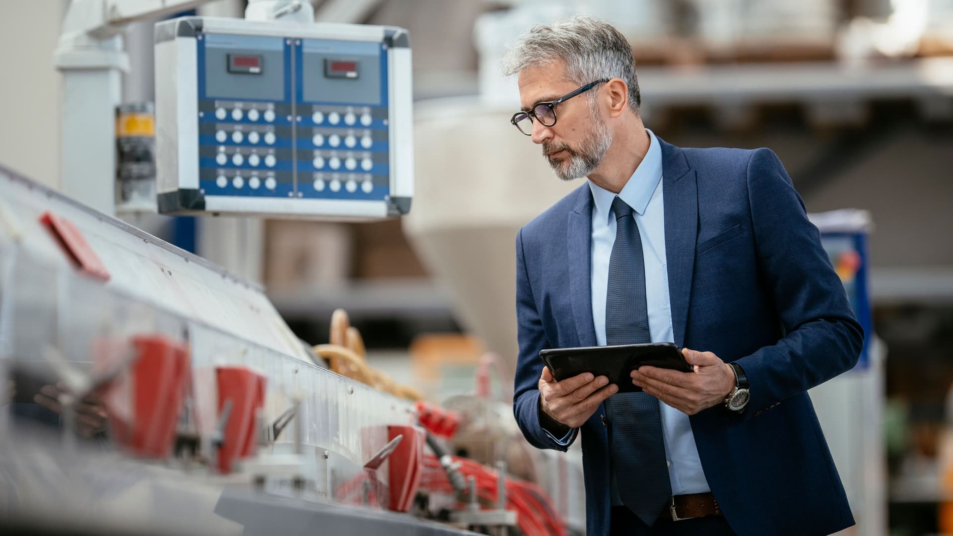 Mittelalter Ingenieur in einer Produktionshalle. Er hat eine Mappe in den Händen und prüft etwas.