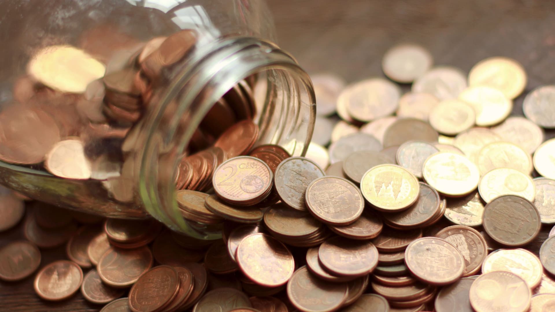 Glas mit ausgeschütteten Eurocent Münzen auf einem Tisch