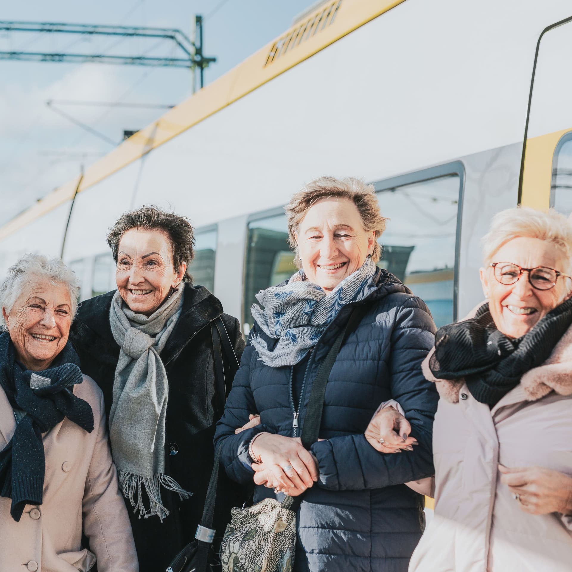 Gruppe Seniorinnen auf dem Bahnsteig vor einem Zug.