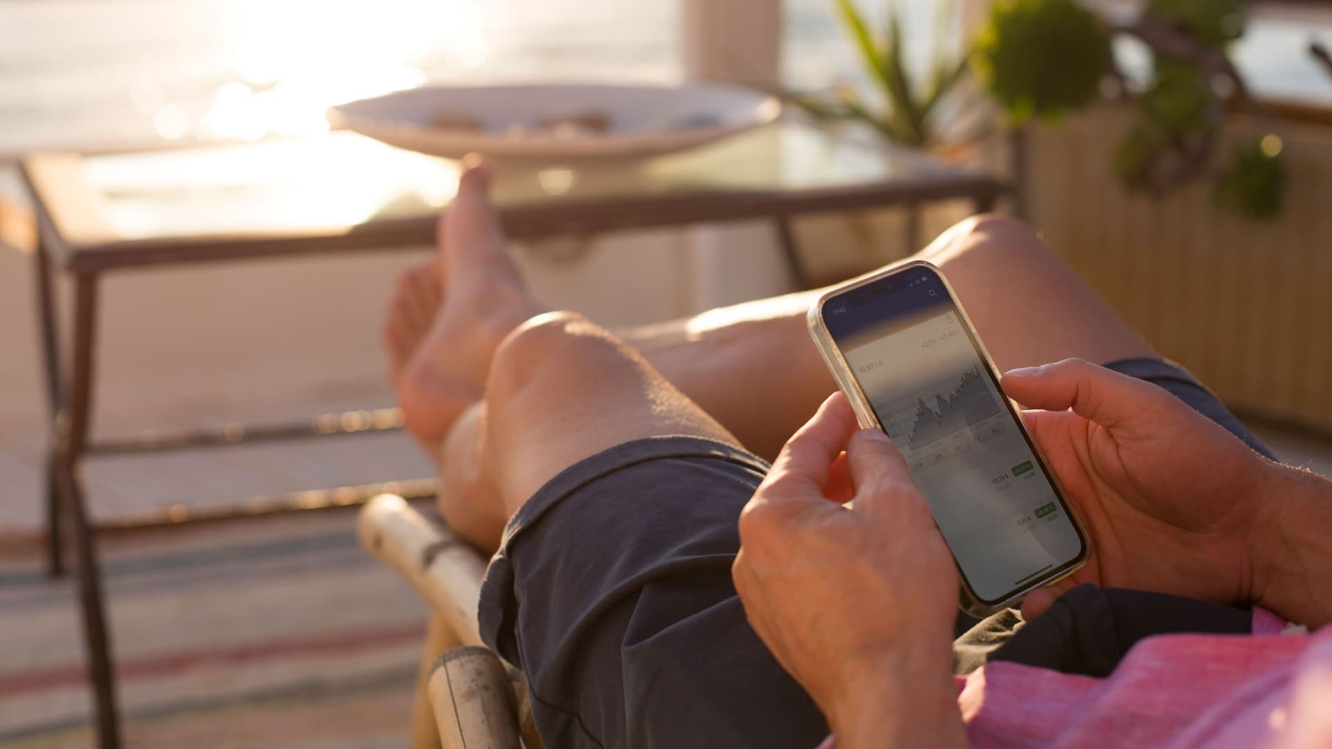 Hände halten ein Mobiltelefon in der Abendsonne