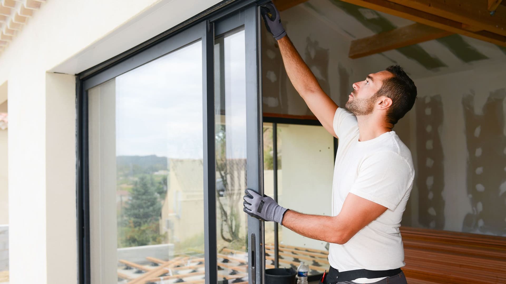 Ein Handwerker montiert eine Glastür und Fenster auf einer Baustelle in einem Wohnhaus.