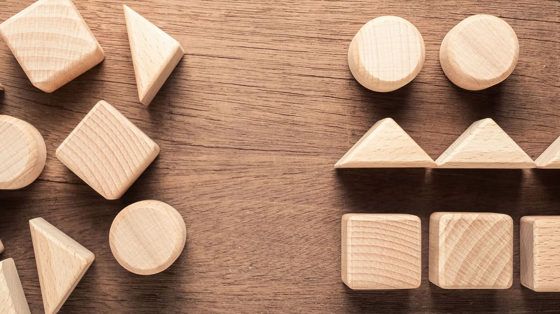 Auf einem Holztisch liegen sortierte und unsortierte Holzklötze in verschiedene geometrischen Formen.