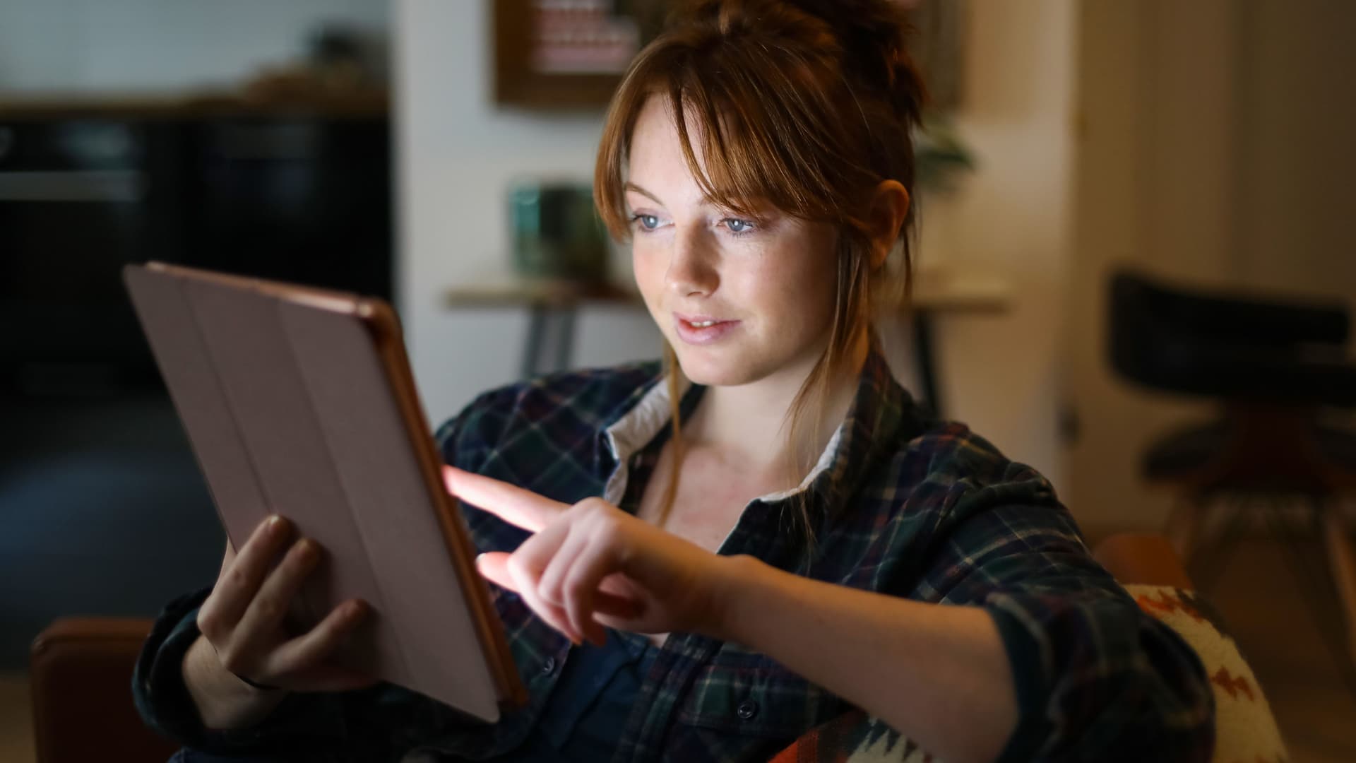 A young woman looking at a digital tablet at home