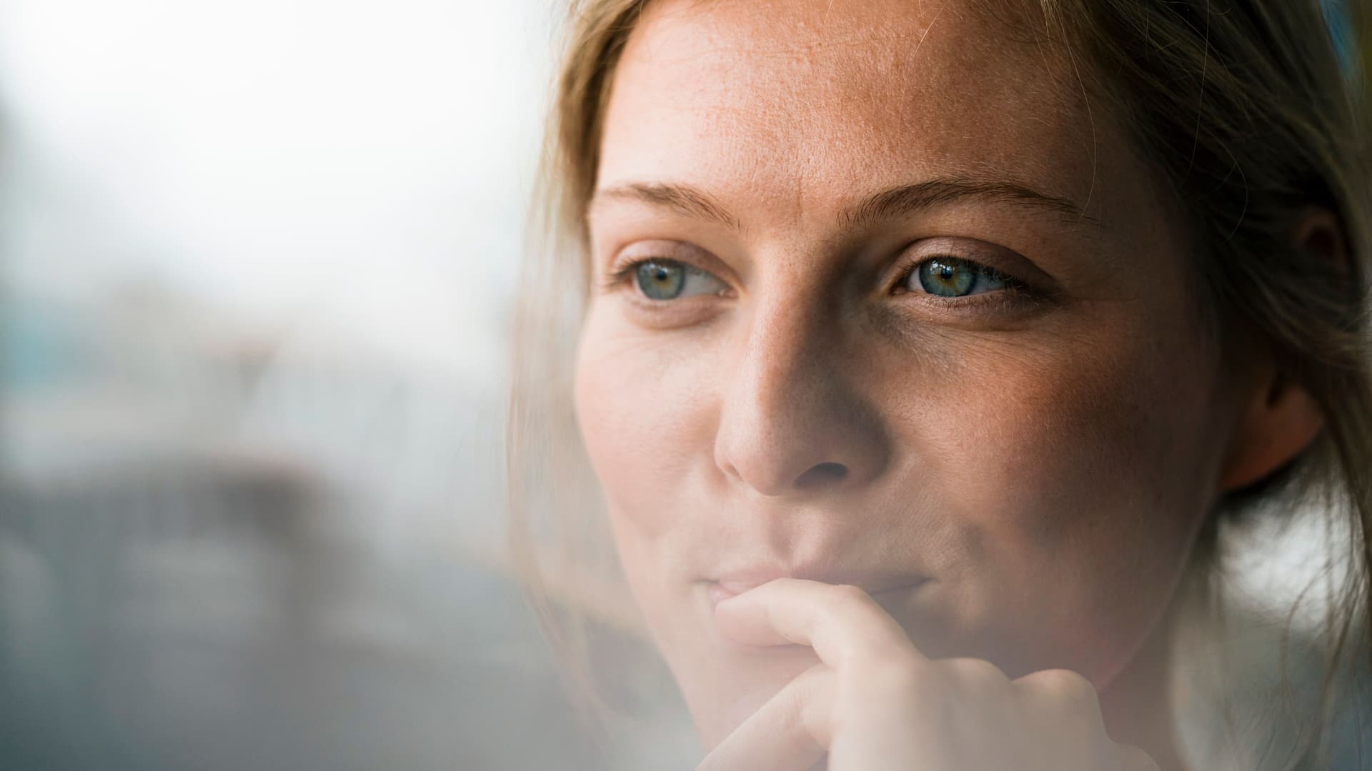 Nahaufnahme einer lächelnden jungen Frau, die zur Seite schaut.