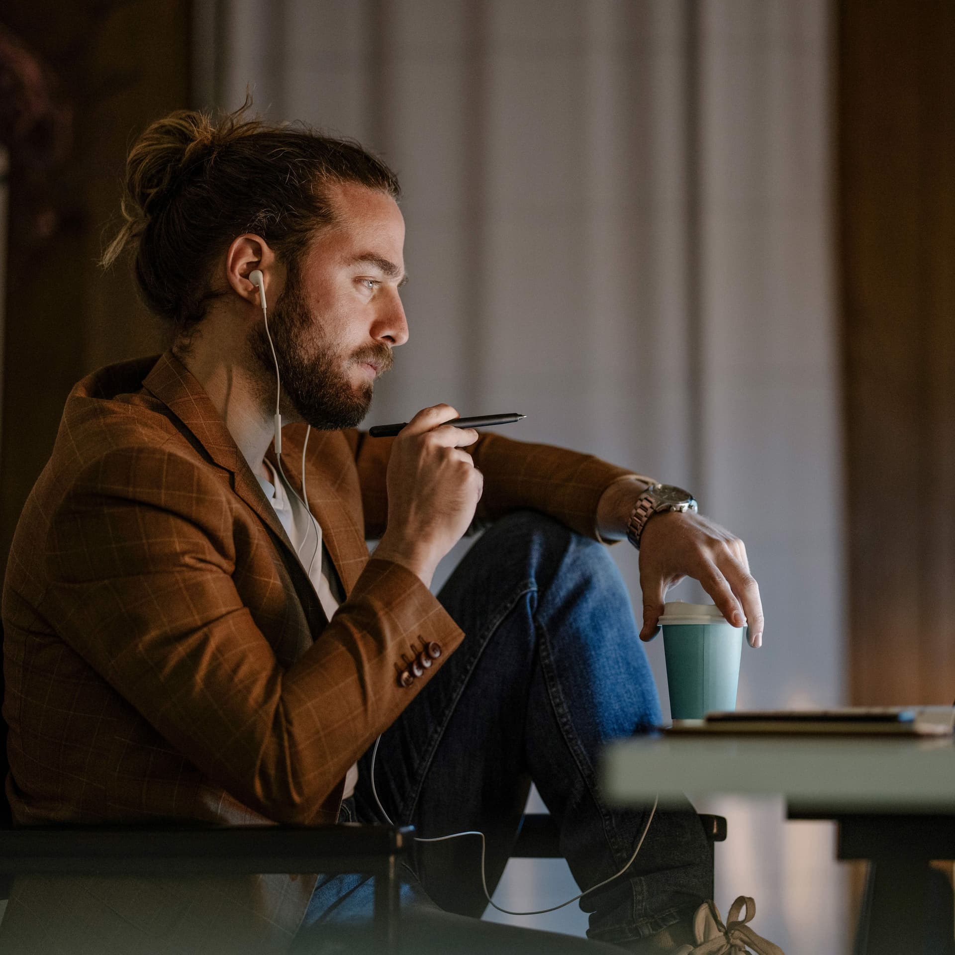 Seitenansicht eines jungen Mannes, der in den Abendstunden entspannt vor seinem Laptop sitzt und diesen anschaut.