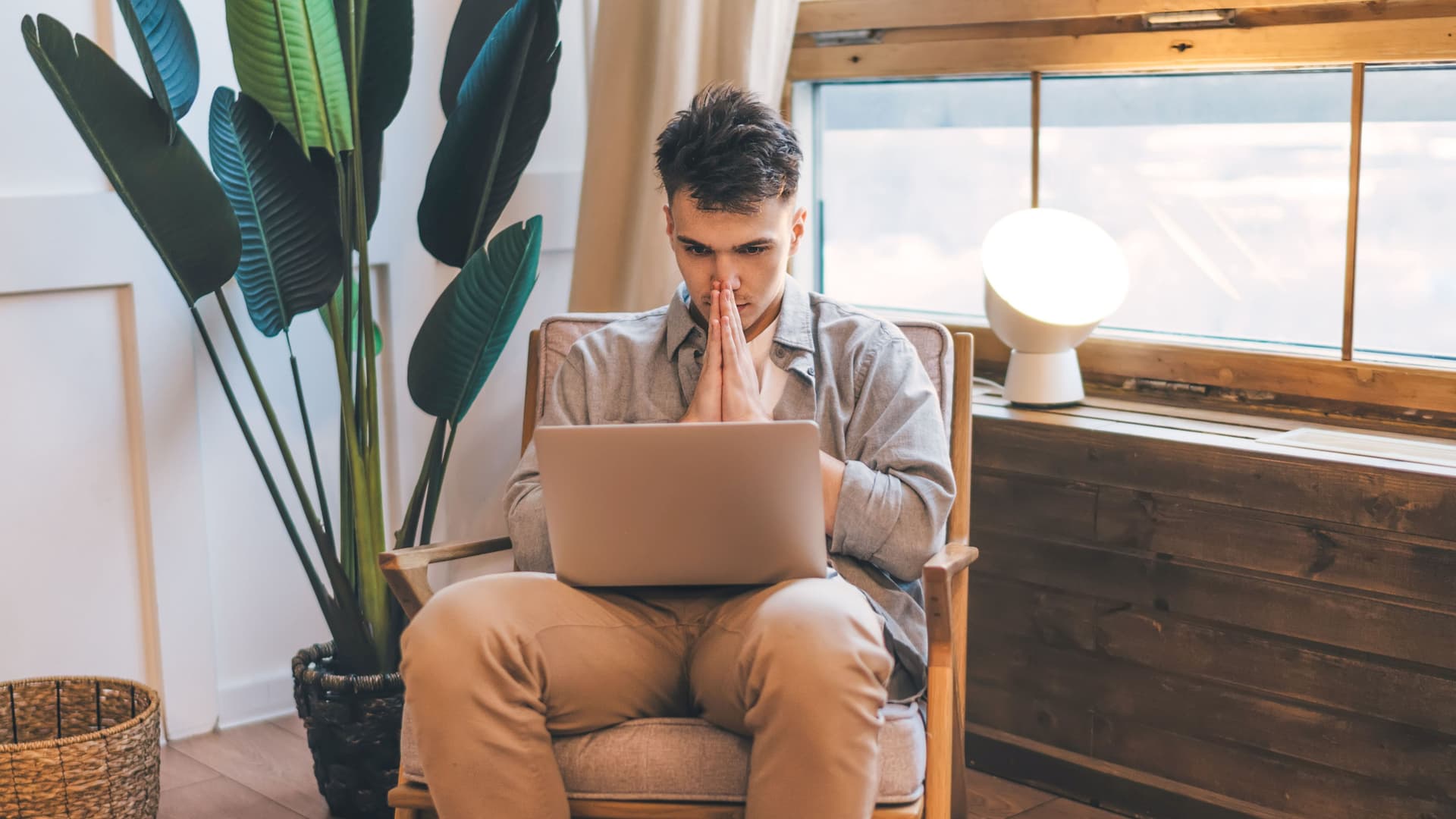 Tipps zum Schutz Ihrer Identität: Junger Mann sitzt in einem Sessel und schaut gebannt auf seinen Laptop.