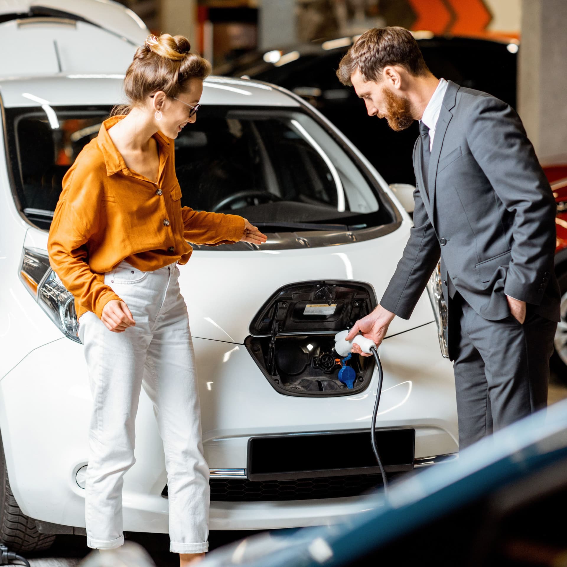 Ein Autoverkäufer zeigt einer Kundin ein Elektroauto.