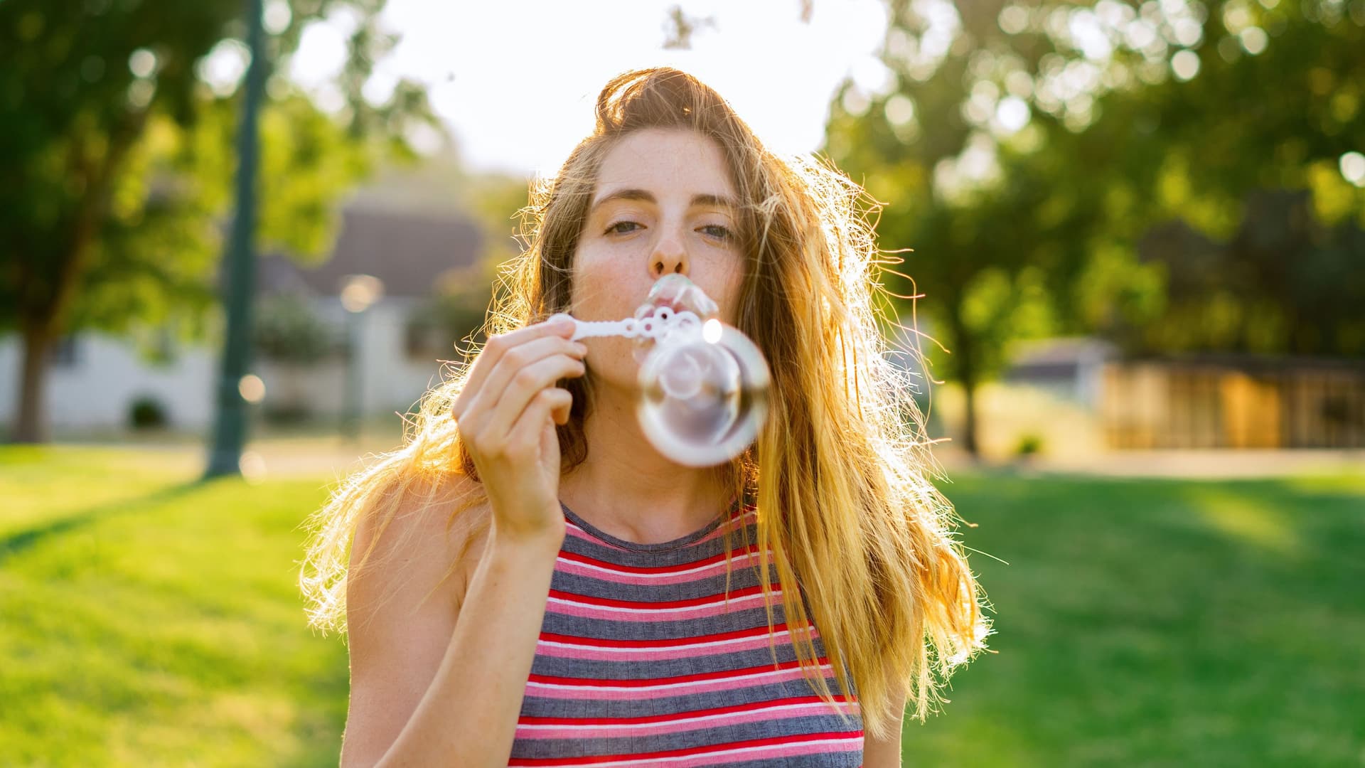 Junge Frau bläst Seifenblasen im Park