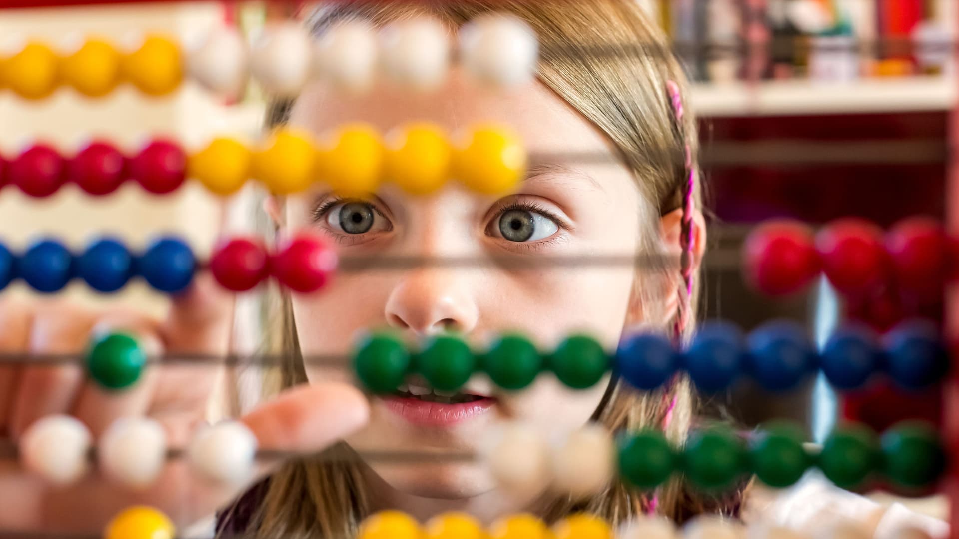 Mädchen spielt mit einem Rechenrahmen (Abakus)