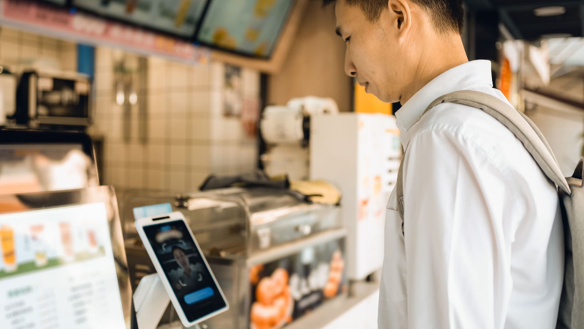 Junger Mann mit Rucksack bestellt per Tablet Essen an einem Foodtruck.