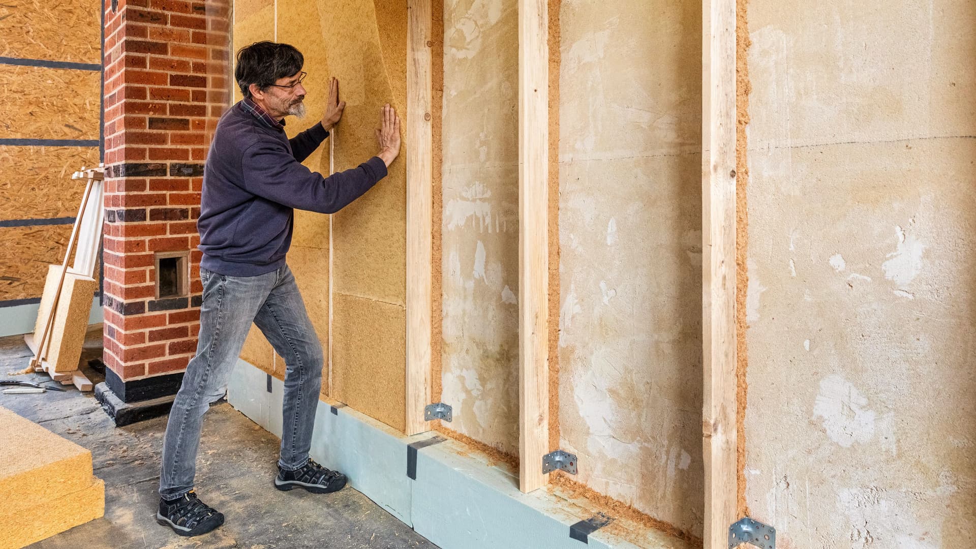 Mann baut Wärmedämmung im Gebäudeinneren ein.