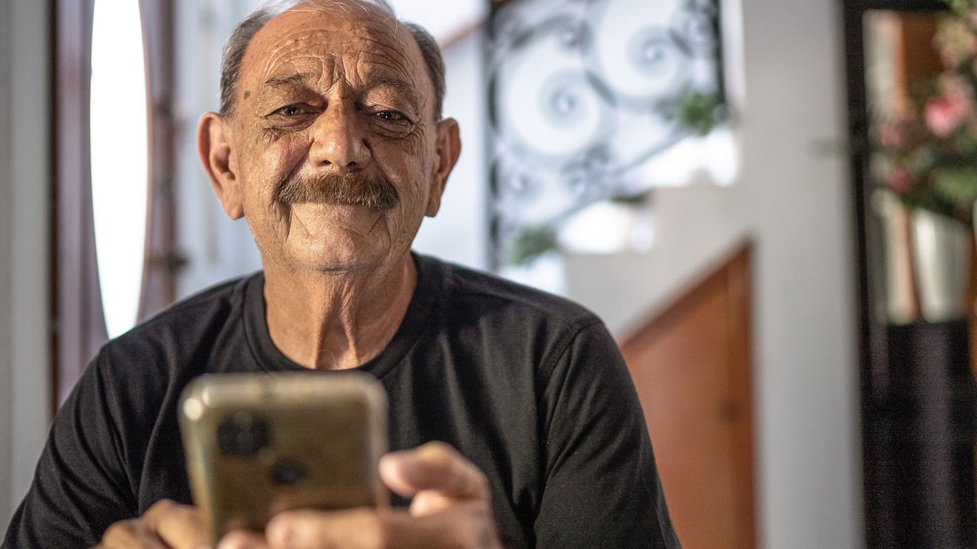 älterer Mann mit Handy innen