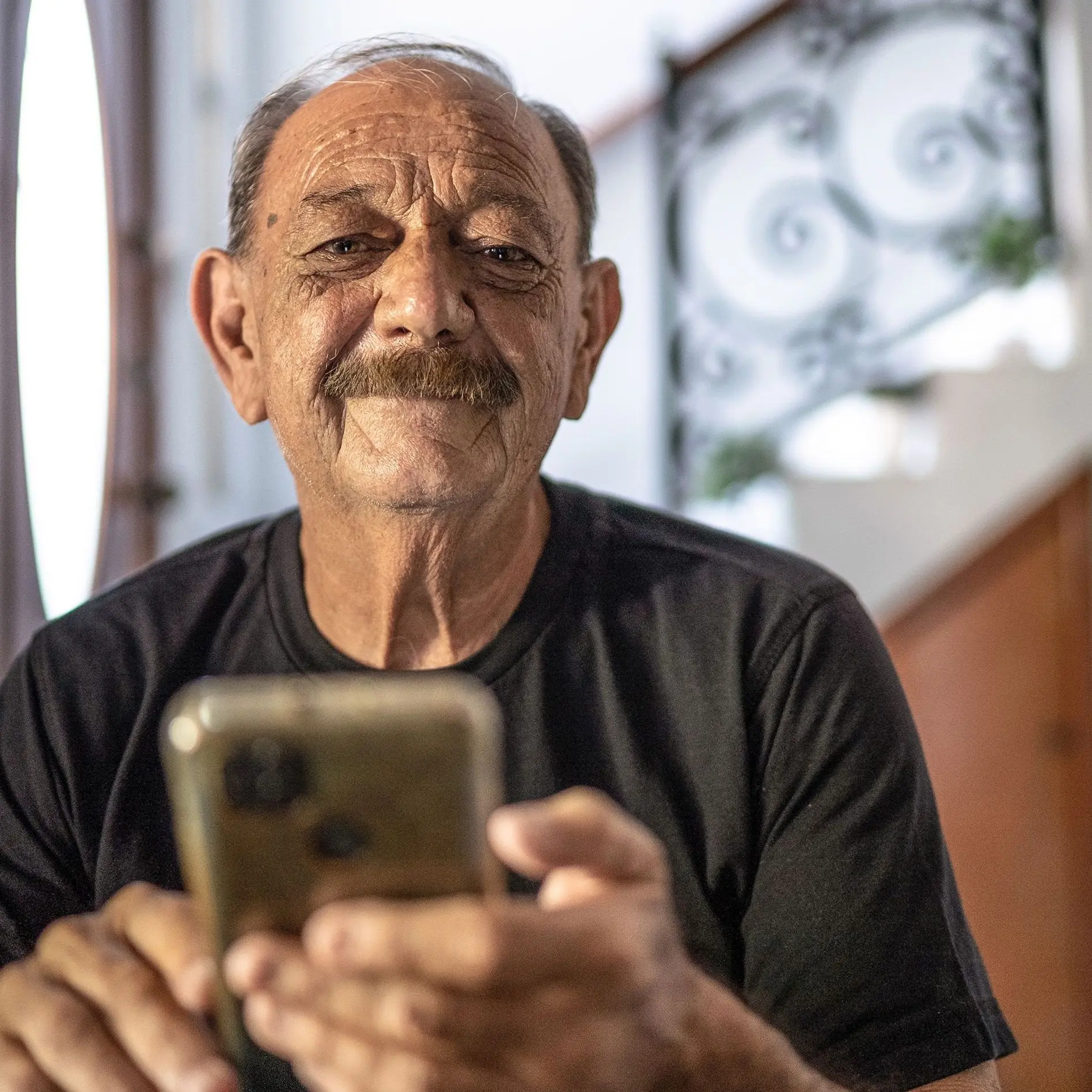 älterer Mann mit Handy innen