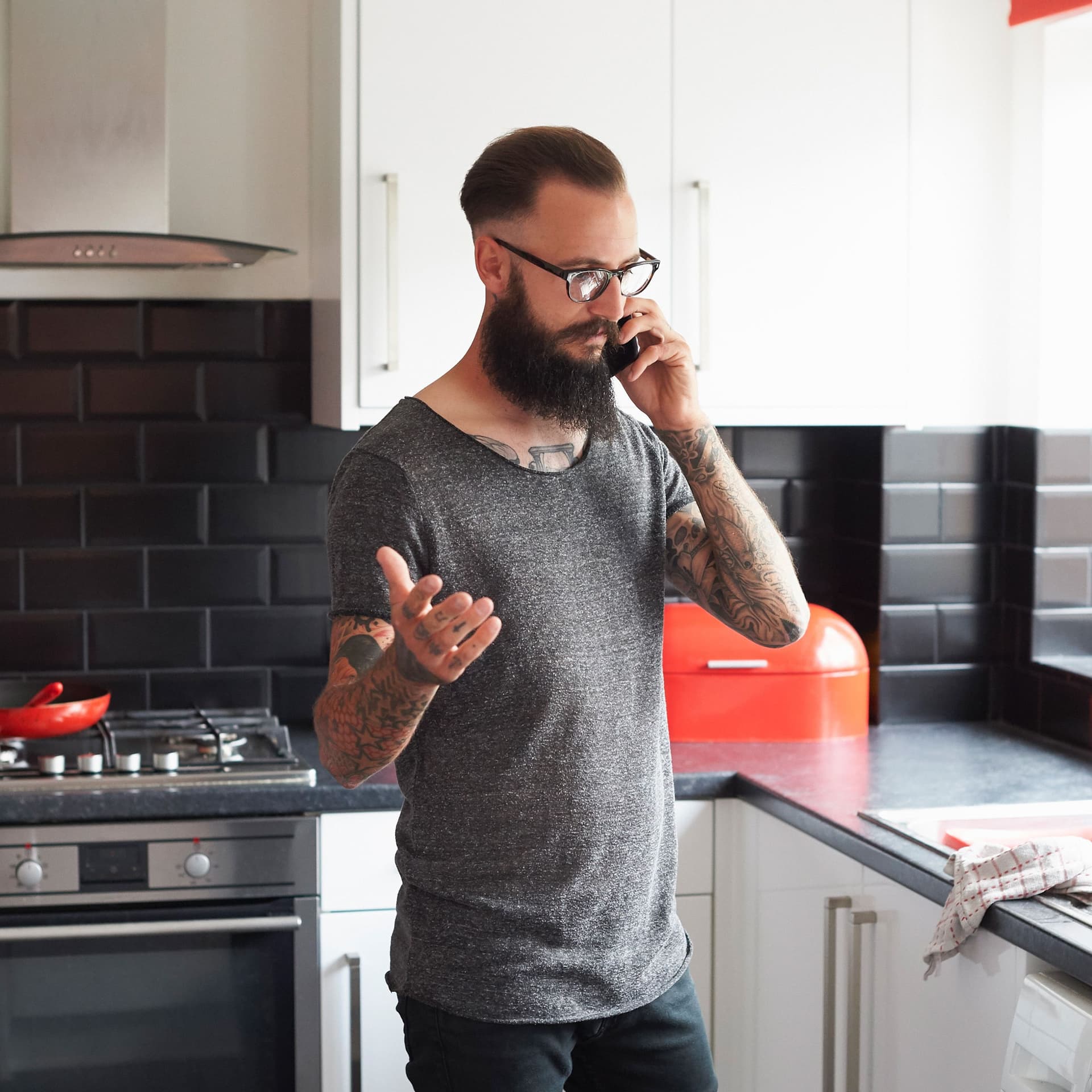 Mann steht in der Kueche und telefoniert mit seiner Versicherung nach Einbruch.