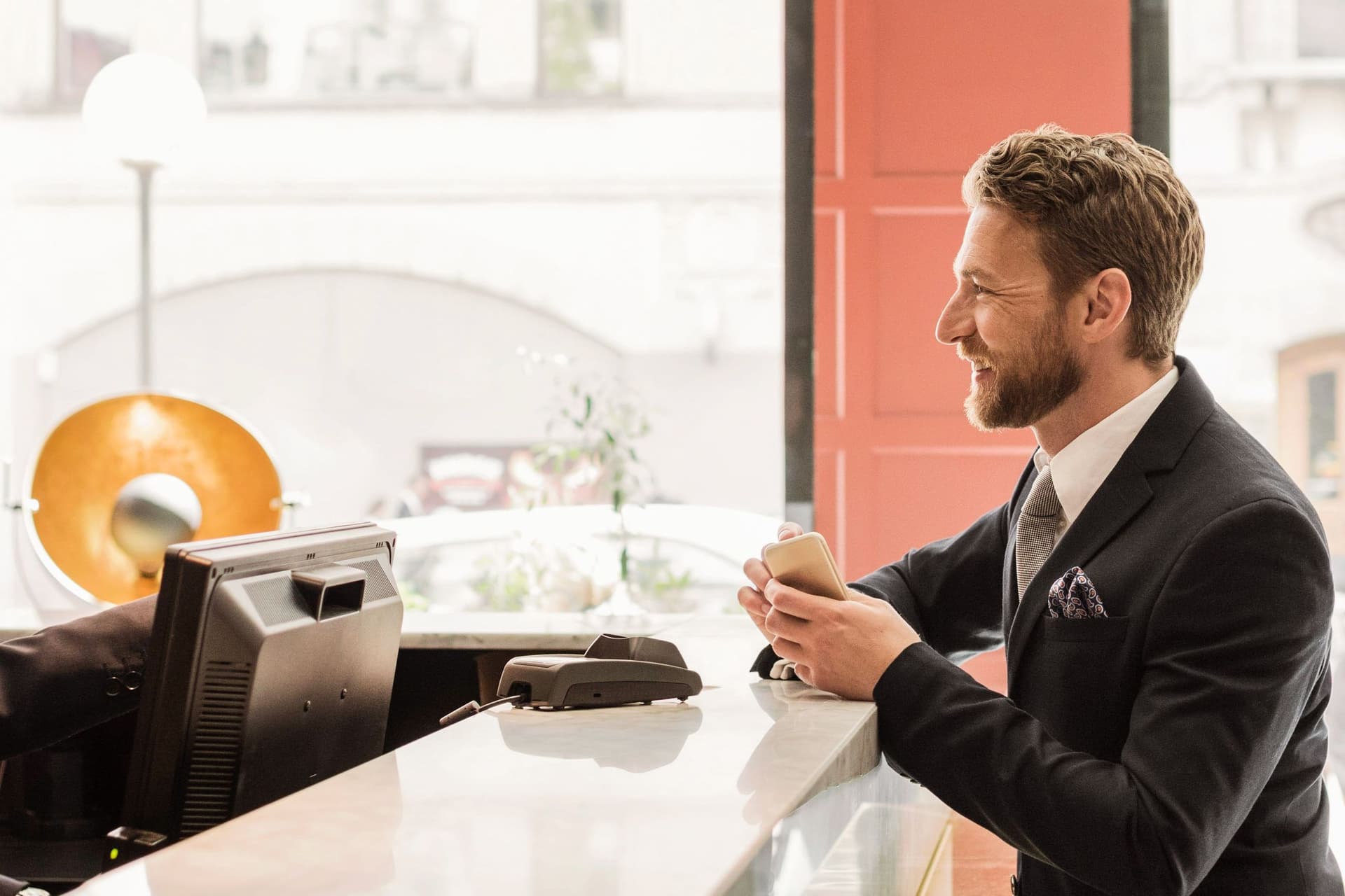 Ein Mann unterhält sich lachend an einer Hotel-Rezeption mit einer Hotelangestellten.