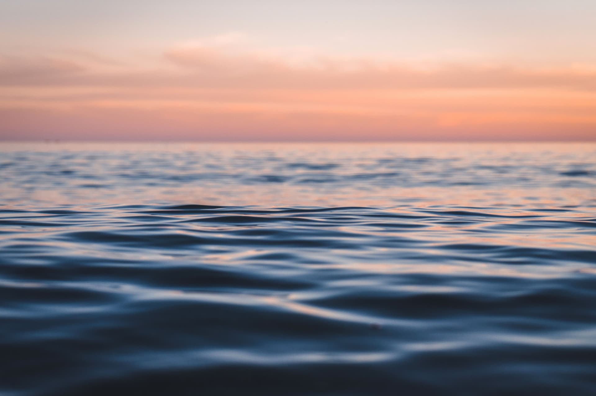 Blick über Wasser mit leichten Wellen auf Dämmerung am Horizont