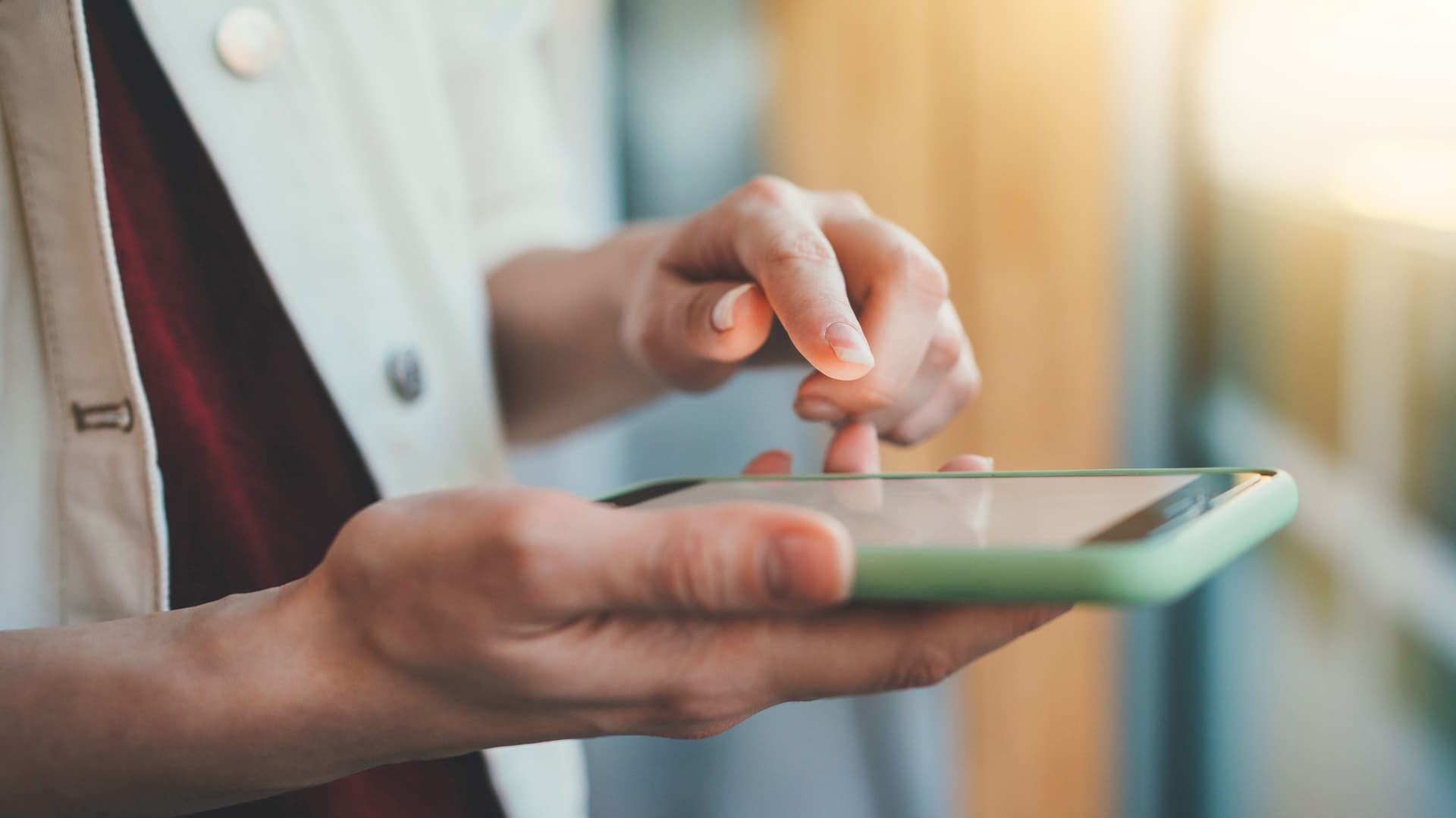 Nahaufnahme einer weiblichen Hand, die auf ein Smartphone tippt.