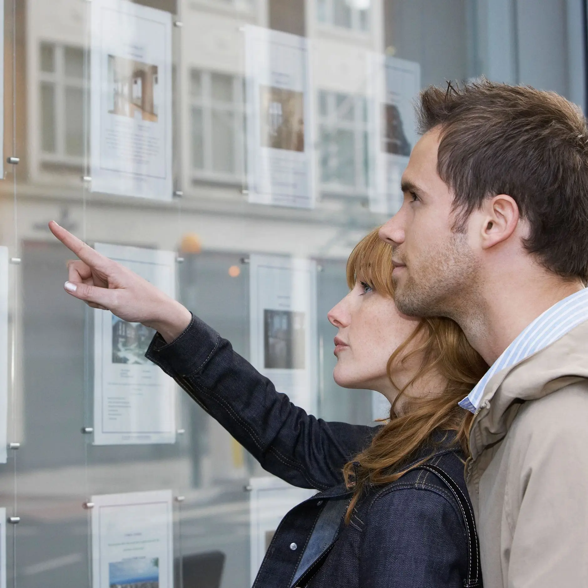 Paar schaut in das Schaufenster eines Immobilienmaklers