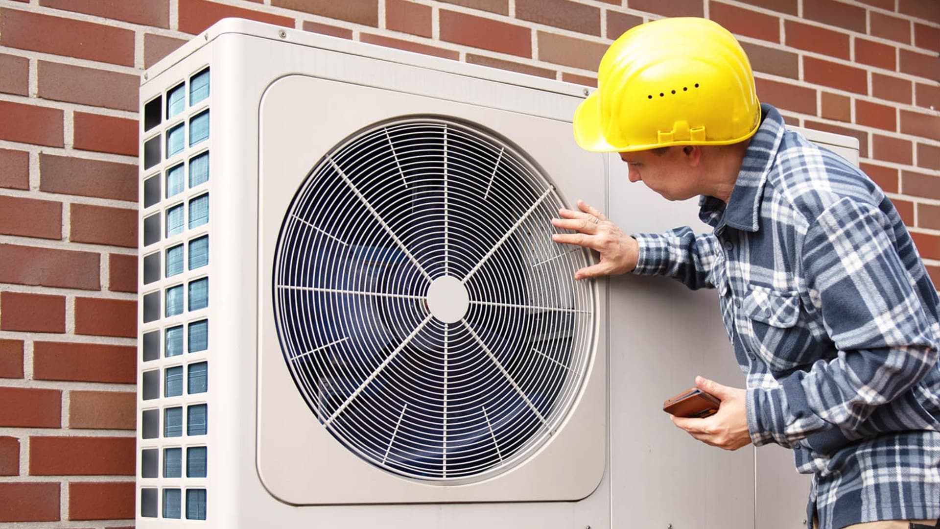 Eine Person steht neben einer modernen, personenkontrollierten Wärmepumpe, die in einem Wohnumfeld installiert ist.