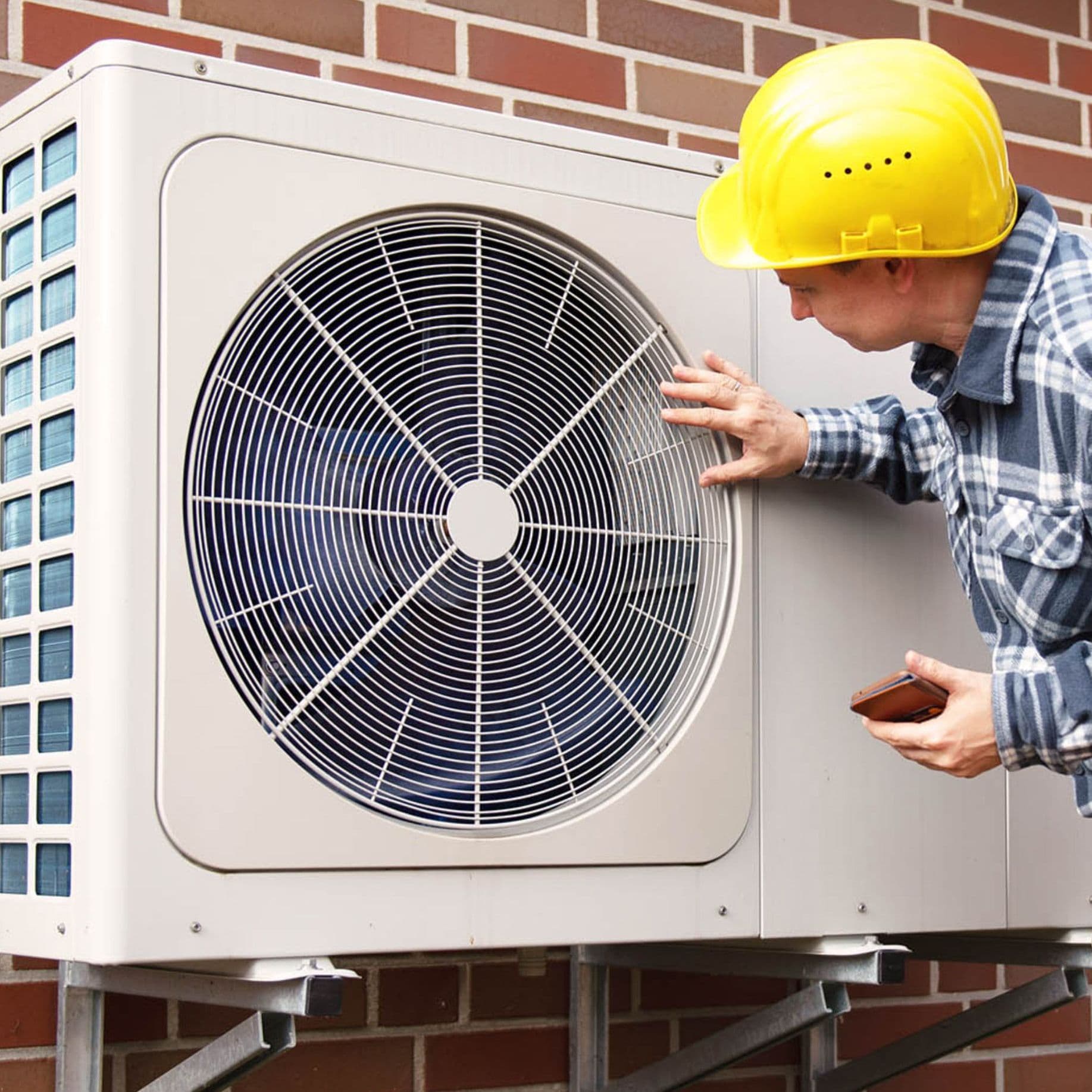 Eine Person steht neben einer modernen, personenkontrollierten Wärmepumpe, die in einem Wohnumfeld installiert ist.