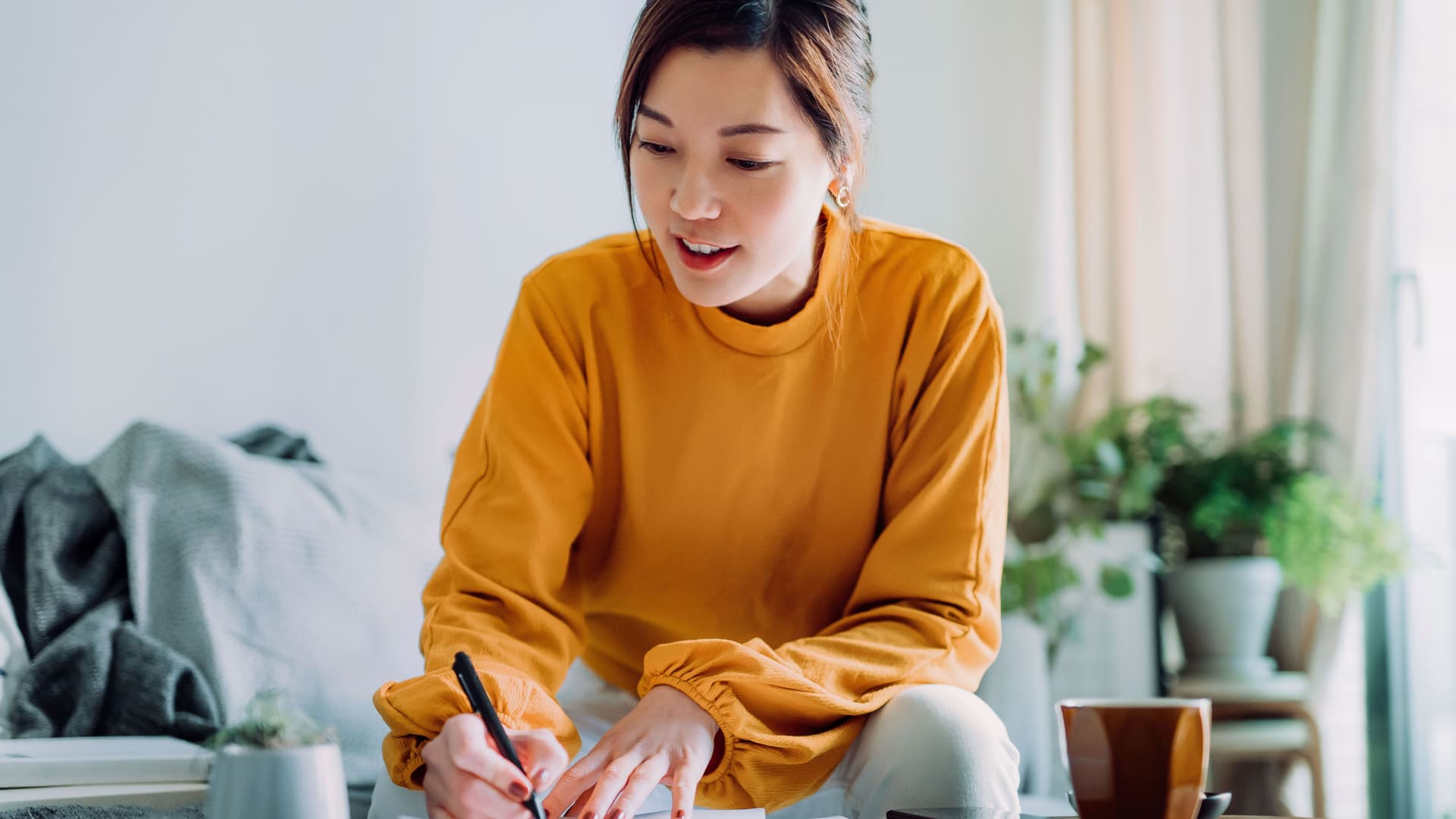 Junge Frau unterschreibt Dokumente auf dem Sofatisch