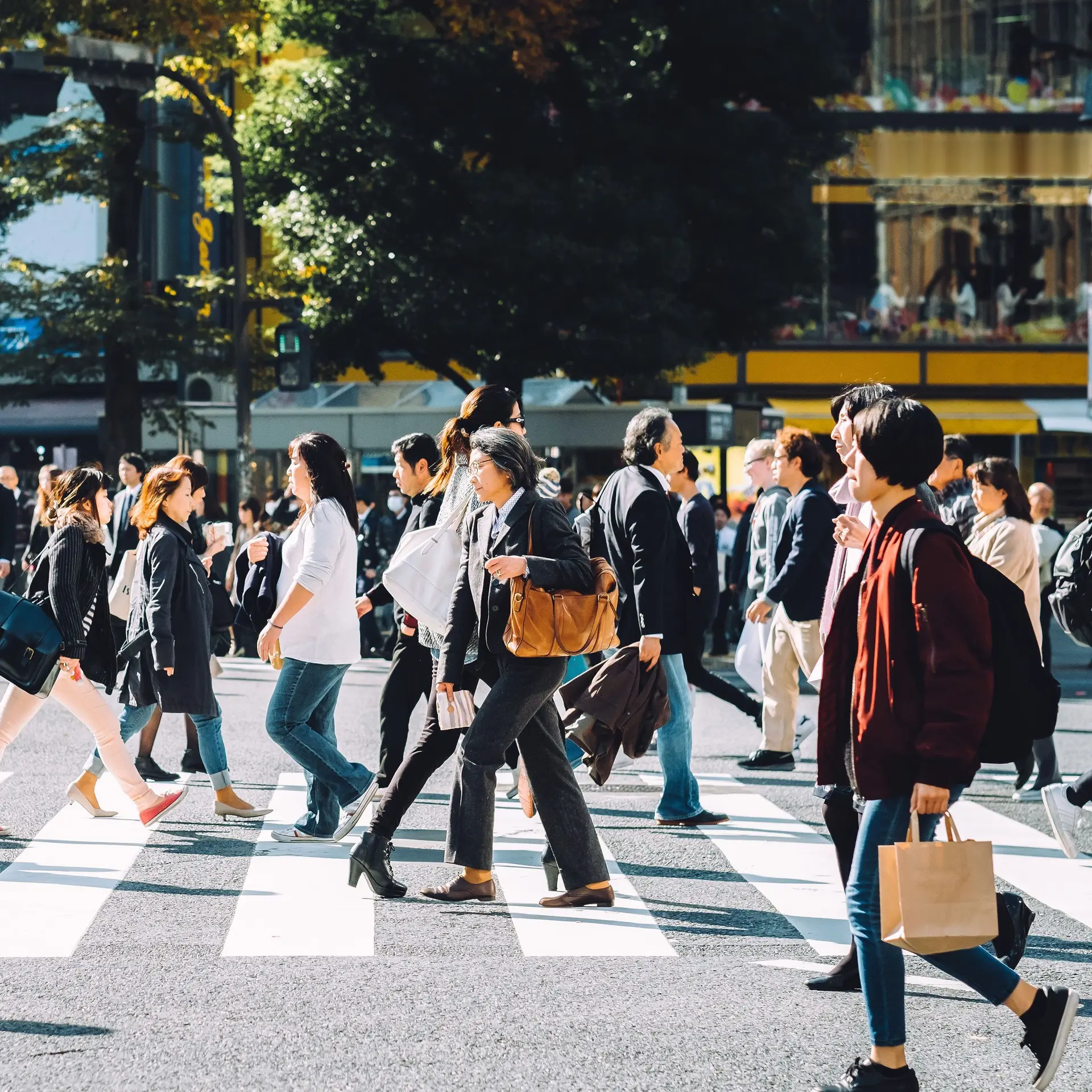 Menschenmenge, die an einem sonnigen Tag die Shibuya-Kreuzung in Tokio überqueren.