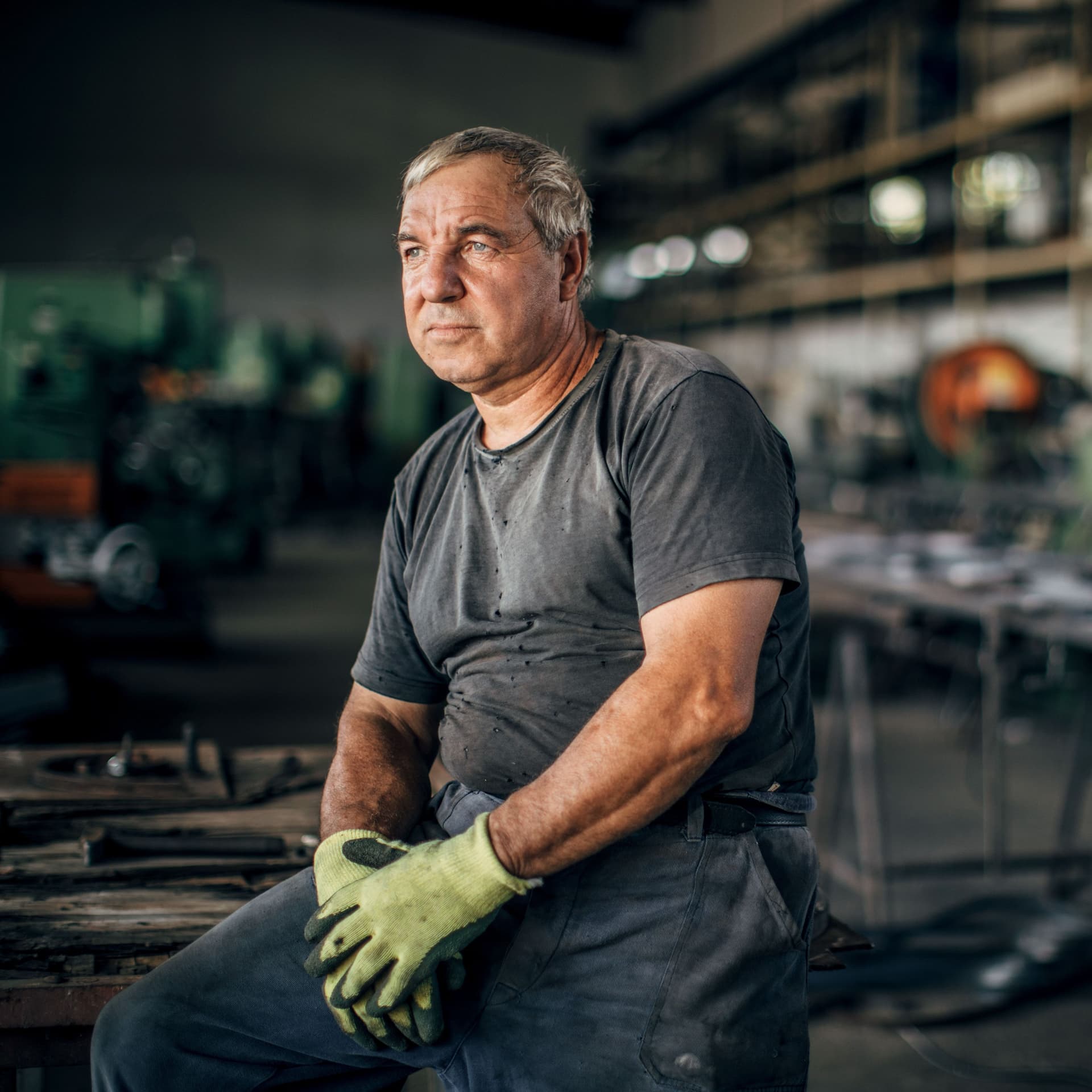 Älterer Mann in Arbeitskleidung in Metallfabrik.