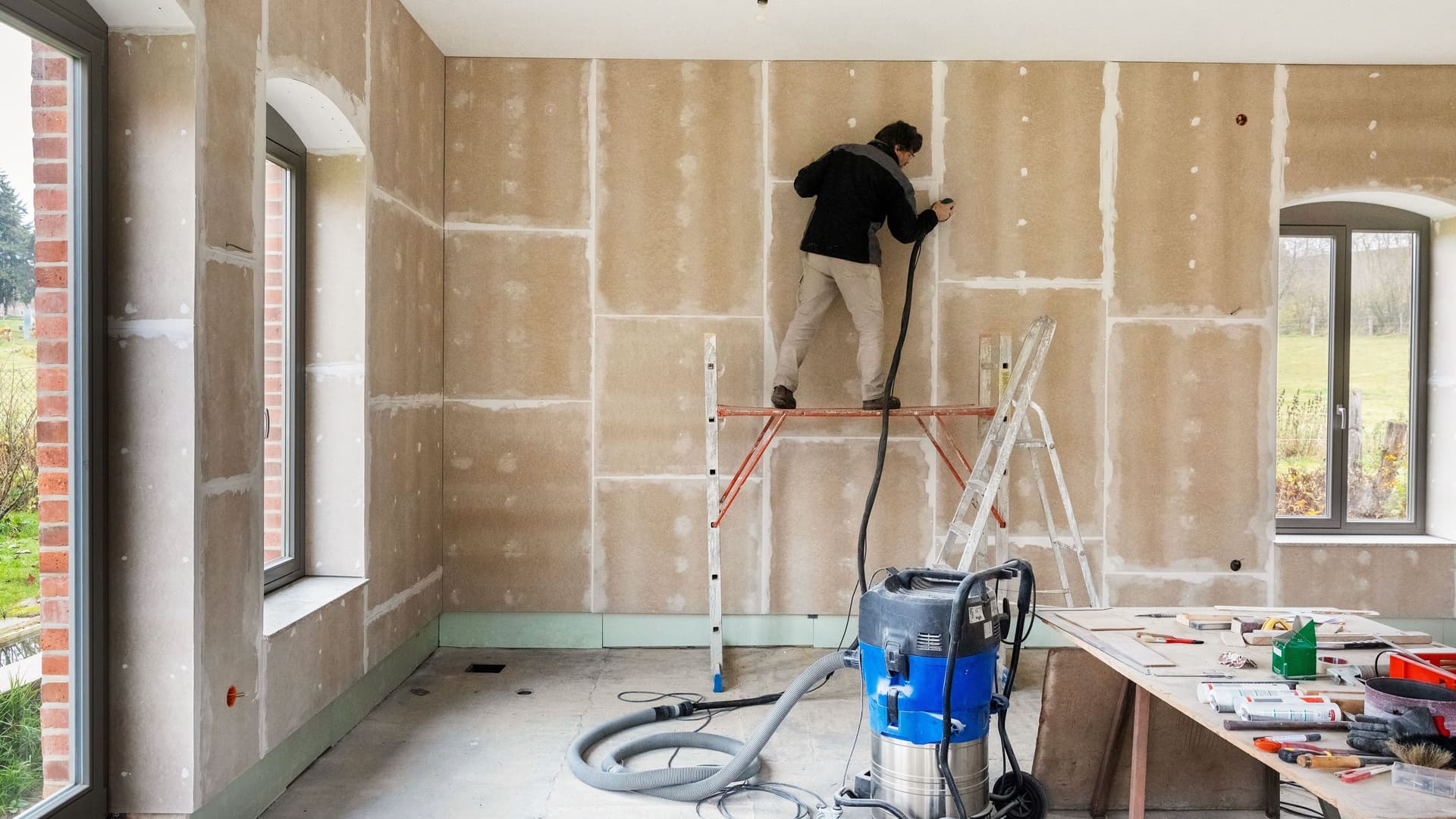 Schleifen der Fugen, Montage von Gipsfaserplatten vor einer Innendämmung mit Holzfaserplatten und OSB-Platten als Dampfbremse