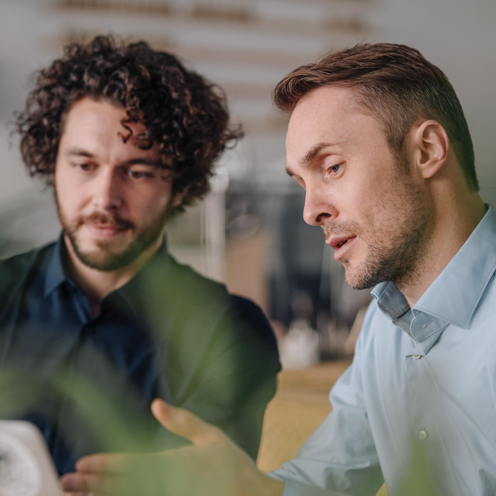 Zwei Männer sitzen vor einem Laptop und gestikulieren.