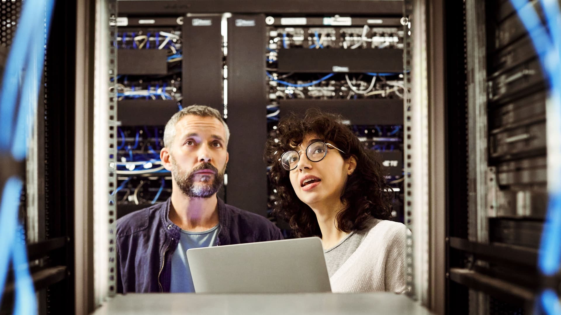 Energie-Einsparpotenziale: Informationstechnologie Mann und Frau unterhalten sich in einem Serverraum und schauen hoch.